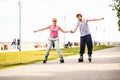 Young couple rollerblading in park holding hands. Royalty Free Stock Photo