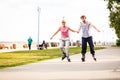 Young couple rollerblading in park holding hands. Royalty Free Stock Photo