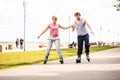 Young couple rollerblading in park holding hands. Royalty Free Stock Photo