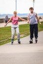 Young couple rollerblading in park holding hands. Royalty Free Stock Photo