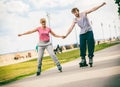 Young couple rollerblading in park holding hands. Royalty Free Stock Photo