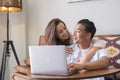 Young couple romancing while working on laptop at home. Woman embracing her husband while he is using laptop in living room. Happy Royalty Free Stock Photo