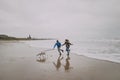 Young Couple Run Along Winter Beach With Their Dog Royalty Free Stock Photo