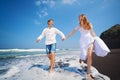 Young couple run by black sand beach along sea surf Royalty Free Stock Photo