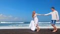 Young couple run by black sand beach along sea surf