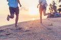 Young couple running along the sandy seashore in the rays of sunset, blurred image perfect background for travel agencies,