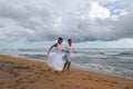 Young couple running along a tropical beach holding hands Royalty Free Stock Photo