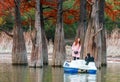 Young couple sailing on paddle boat and taking photos by wood of red swamp cypresses growing in Sukko lake by Anapa, Russia. Water