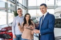 Young couple with salesman near new car signing contract Royalty Free Stock Photo