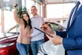 Young couple with salesman near new car signing contract Royalty Free Stock Photo