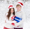 Young couple in santa claus hats hugging and holding gifts Royalty Free Stock Photo