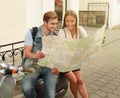 Young Couple with scooter looking at map. Royalty Free Stock Photo