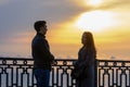 Young couple by the sea at sunset communicates while respecting social distance