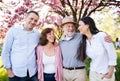 Young couple with senior parents walking outside in spring nature.