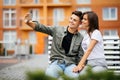 Young couple in shopping. Handsome young couple sitting on the bench and taking a selfie with a mobile phone. Royalty Free Stock Photo