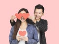 Young couple showing red hearts and standing over pink background Royalty Free Stock Photo
