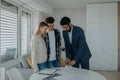 Young couple signing contract when buying their new home and receiving keys from real estate agent. Royalty Free Stock Photo