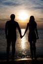 Young couple silhouette on a sea beach holding hands and lookin Royalty Free Stock Photo