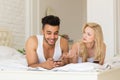 Young Couple Sit In Bed, Happy Smile Hispanic Man Frustrated Woman Using Cell Smart Phone Royalty Free Stock Photo