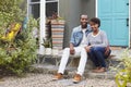 Young couple sit looking to camera outside their new house Royalty Free Stock Photo