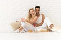 Young Couple Sit On Pillows Floor, Happy Hispanic Man And Woman Breakfast Tray Lovers In Bedroom Royalty Free Stock Photo