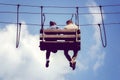 Young couple siting dangling legs on a hanging bench in adventure rope park. Romantic meeting in the skies