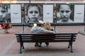 A young couple sits on a bench on a city street