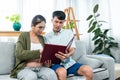 A young couple sits on a sofa in the living room with a pregnant woman and a man holding a folder in his hand, Royalty Free Stock Photo