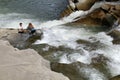 Young couple sits on stones near a rapid mountain river