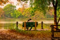 Young Couple sitting in an autumn park bench in Lakeshore. Falling in love in Maple leaf garden. Relaxation and romantic activity Royalty Free Stock Photo