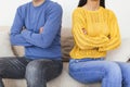 Young couple sitting back to back after a fight on the sofa. Young couple in fight with arms crossed sitting on couch after Royalty Free Stock Photo