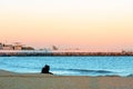 Young couple sitting on beach in front of calm sea at sunset Royalty Free Stock Photo