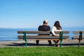 Young couple sitting on bench in park. Rear view. Back view of a couple on park bench by the sea Royalty Free Stock Photo