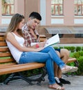 Young couple sitting on a bench reading a map Royalty Free Stock Photo