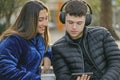 Young couple sitting on the bench in a square with mobile phone and headphones Royalty Free Stock Photo