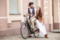 Young couple sitting on a bicycle against the wall