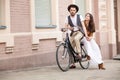 Young couple sitting on a bicycle against the wall