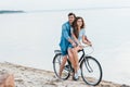 young couple sitting on bicycle on beach