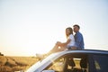 Young couple sitting on car and looking straight ahead Royalty Free Stock Photo