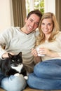 Young couple sitting with cat on sofa Royalty Free Stock Photo