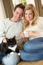 Young couple sitting with cat on sofa Royalty Free Stock Photo