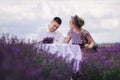 Young couple are sitting on chairs at table and relaxing in lavender field. woman in purple dress and flower`s wreath with man Royalty Free Stock Photo