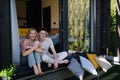 Young couple sitting with cup of coffee and cuddling in terrace in their new home in tiny house in woods, sustainable