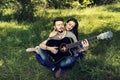 Young couple sitting down on a purple blanket and playing on a guitar Royalty Free Stock Photo