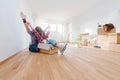 Young couple sitting on the floor of empty apartment. Move in to new home. Royalty Free Stock Photo