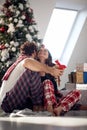 A young couple sitting on the floor expressing love and giving Xmas presents. Christmas, relationship, love, together Royalty Free Stock Photo