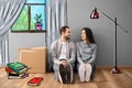 Young couple sitting on floor near box indoors and imagining interior of new house. Moving day Royalty Free Stock Photo