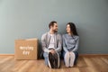 Young couple sitting on floor near box indoors. Moving into new house Royalty Free Stock Photo