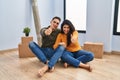 Young couple sitting on the floor at new home approving doing positive gesture with hand, thumbs up smiling and happy for success Royalty Free Stock Photo