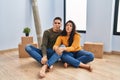 Young couple sitting on the floor at new home making fish face with lips, crazy and comical gesture
